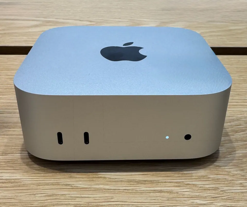 Mac mini M4 đặt trên bàn gỗ, mặt trước có hai cổng USB-C