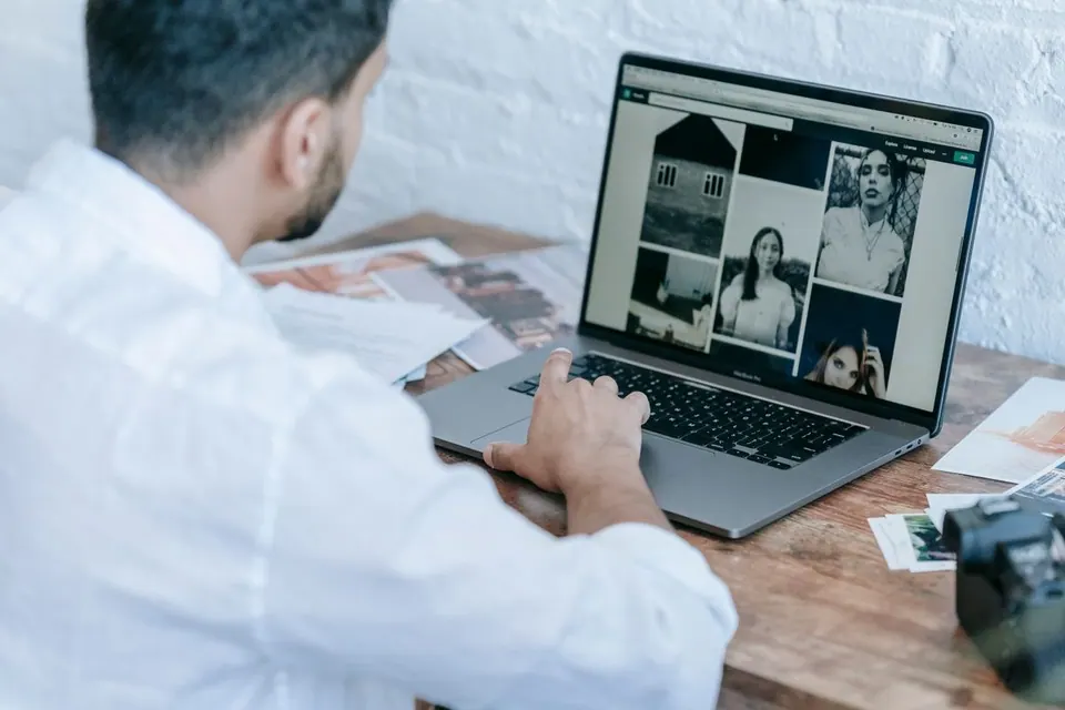 Người dùng xem ảnh chân dung trên MacBook tại bàn làm việc