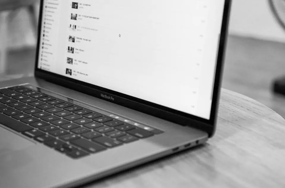 MacBook Pro đặt trên bàn gỗ tròn, ảnh đen trắng