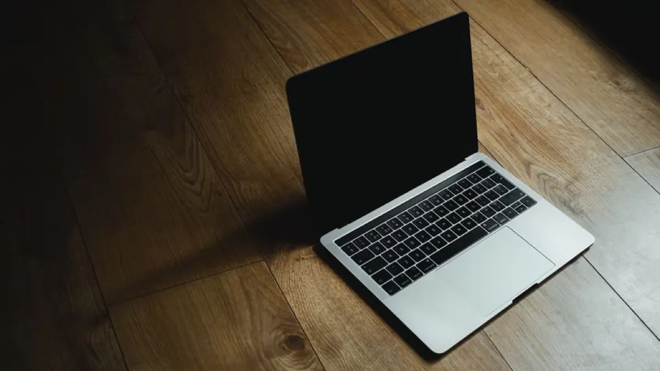 MacBook đặt chéo trên sàn gỗ dưới ánh sáng dịu