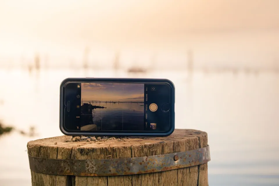 iPhone đặt ngang đang mở app Camera chụp cảnh hoàng hôn