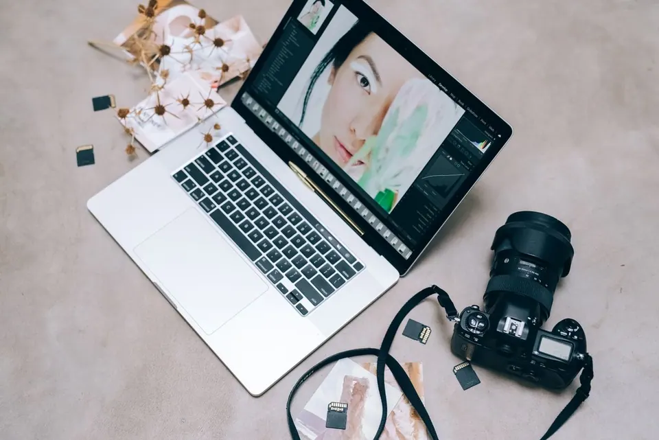 MacBook mở ảnh chân dung bên cạnh máy ảnh và thẻ nhớ trên bàn