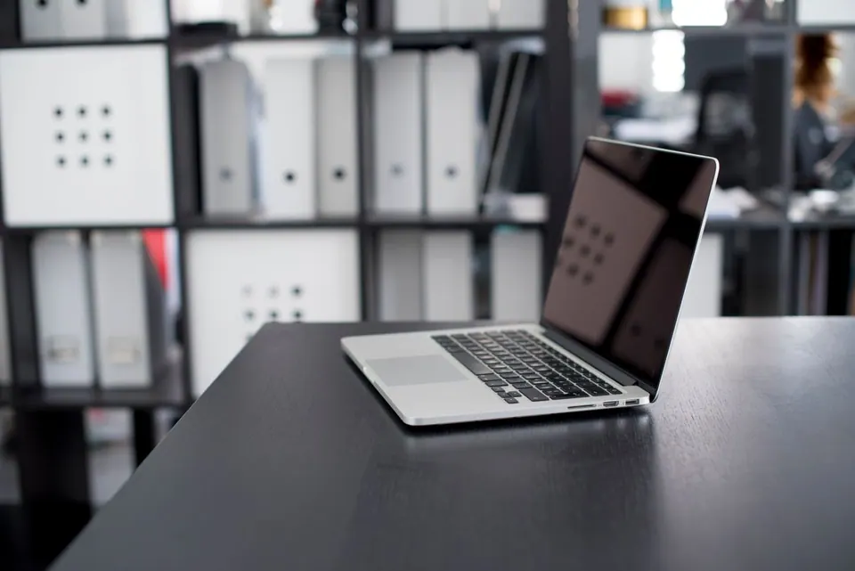 MacBook Pro đặt trên bàn làm việc trong văn phòng có tủ hồ sơ