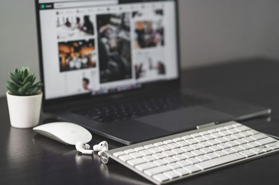 MacBook với chuột, bàn phím không dây và AirPods trên bàn làm việc